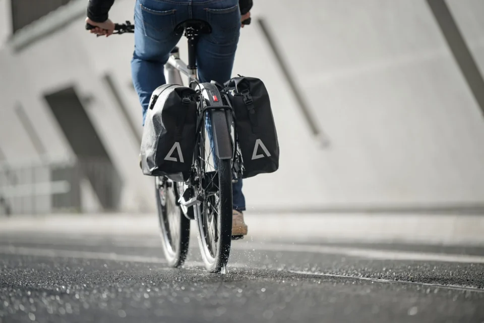 A hybrid bike with pannier bags riding on tarmac through an urban environment